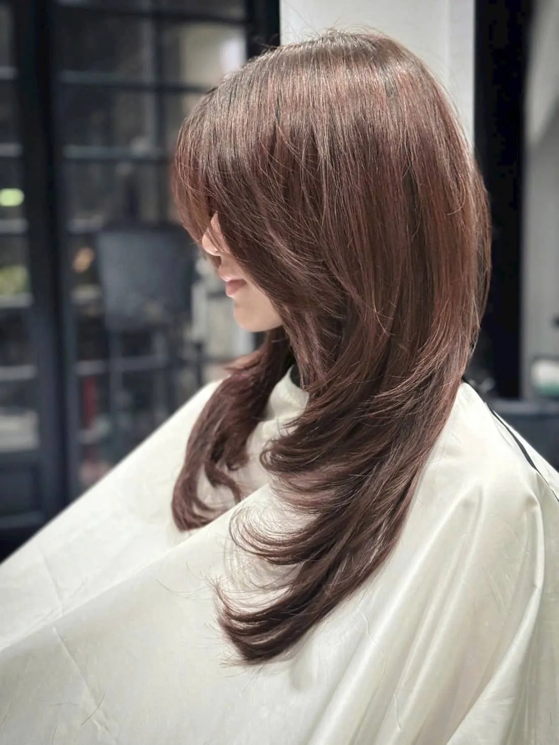 Long layered copper-brown haircut with curtain bangs, finished at Nien Is New hair salon in Da Nang